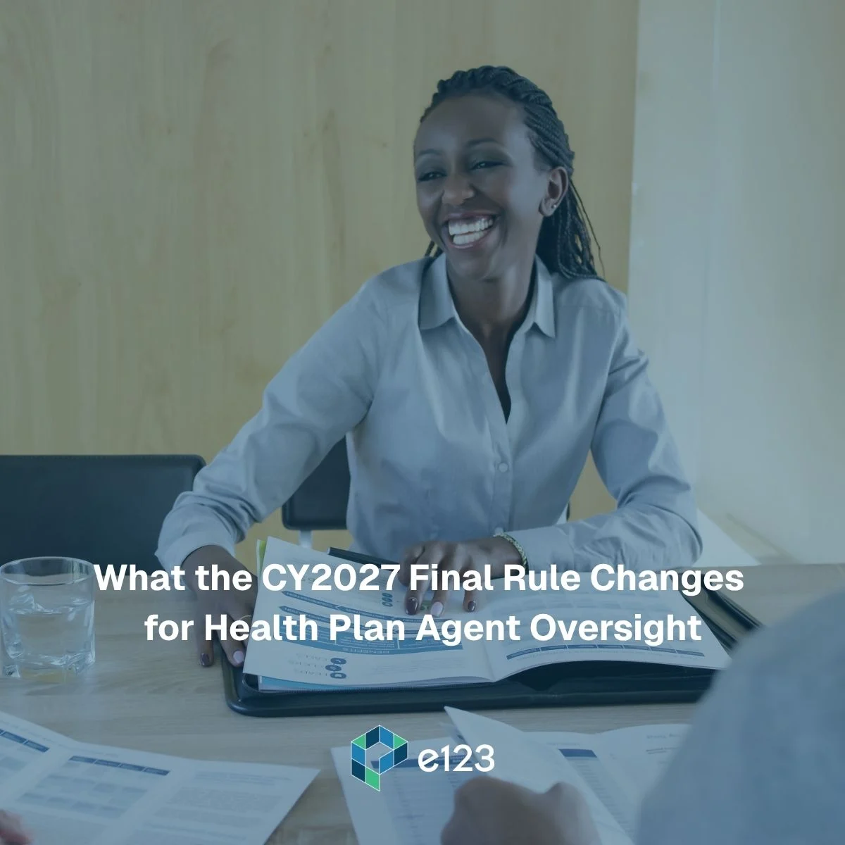 Smiling woman in business attire sits at a table with documents, engaging in discussion about Health Plan agent oversight. Text overlay reads, What the CY2027 Final Rule Changes for Health Plan Agent Oversight. e123 logo at the bottom.